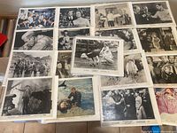 A collection of mostly black and white vintage 8 x 10 movie still photographs arranged on a table showing actors and scenes.