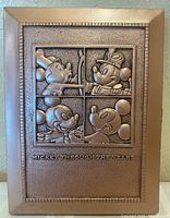 Front of copper-colored metal picture frame with embossed four Mickey Mouse designs labeled 'Mickey Through the Years'