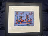 Front view of the framed art print with the colorful print titled 'Wild Family' by Norval Morrisseau showing figures in a canoe with bold colors and black outlines