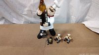 Chef figure holding bottle with accessories displayed
