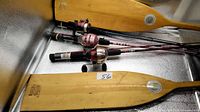 Wood paddles and three spincast rod-reel combos on metal surface