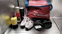 Front view of all items: cooler bag, golf shoes, slides, thermos bottles, espresso maker