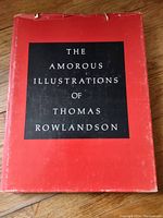 Front view of the book with red and black dust jacket titled 'The Amorous Illustrations of Thomas Rowlandson'