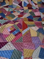 Close-up showing the patchwork of colorful satin fabric pieces with decorative embroidery stitches.