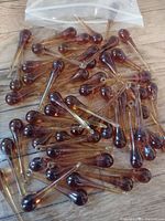Photo of numerous amber glass chandelier drops spread on a wooden surface with a plastic zip bag partially visible.