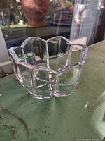 Photo showing clear crystal bowl with scalloped rim and faceted geometric pattern. Outdoors setting with reflected light to highlight heavy cut crystal design.