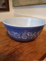 Full view of vintage blue Pyrex bowl showing the white floral pattern on the exterior and smooth glossy white interior.