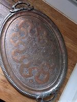 Full view of the oval copper tray with decorative handles and engraved floral/geometric patterns.