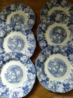 Six blue and white plates laid out in two columns of three, showing detailed floral border and central scenic design.