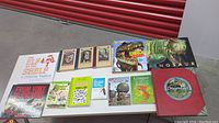 Photo showing an assortment of 14 books laid on a table including Elf on the Shelf, dinosaur books, Diary of a Wimpy Kid, A Series of Unfortunate Events, and Dragonology.