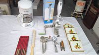 Full lot showing coffee maker, letter holder, meat grinder, ice cream scoop, and other kitchen tools on table