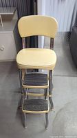 Front angle view of the MCM step stool showing the yellow cushioned seat and backrest with two steps.
