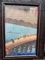 Close up of framed art print showing detailed view of figures on bridge, rain, and signatures