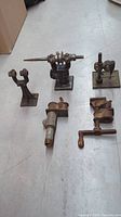 Top view of six vintage metal tools shown on floor with industrial shapes, rust, and mechanical components.