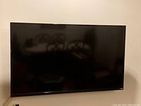 Front view of 48-inch Vizio TV mounted on wall, screen off, showing slim bezel and overall condition.