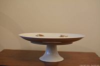 Side view of the white porcelain cake stand with pedestal base showing profile and height.