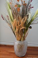 Full view of the vase filled with dried decorative grasses showing overall shape and size.