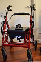 Front view of red folding rollator walker showing padded seat and storage pouch with Drive Medical branding.