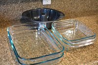 2 oblong Pyrex baking dishes, 2 square Pyrex baking dishes, and a black non-stick tube cake pan on kitchen counter
