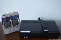 Sony SLV-D281 DVD and VHS combo player with remote control on top, and Terk wireless remote control extender in original packaging to the side, all on tabletop.