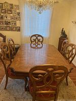 Full view of wood dining table and six chairs under chandelier