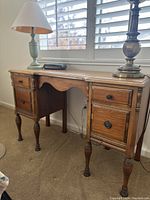 Full view of the vintage wooden desk showing four drawers and turned legs with natural wood finish.