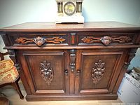 Front view of the walnut buffet showing carved pulls and decorative carved panels on double doors.