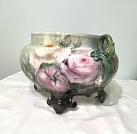 Front angle showing pink floral decoration, green swan handle, and ornate foot