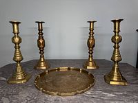 Front view of two pairs of antique brass candlesticks with a solid brass tray on a table, showing their height and shape.