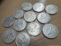 Twelve Canadian silver quarters all showing the reverse side with the caribou design visible on each coin.