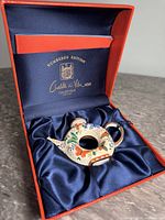 Miniature enamel tea pot nestled inside satin-lined orange box with Charlotte di Vita branding on interior.