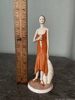 Full view of the porcelain figurine with a ruler showing height of 8.5 inches.