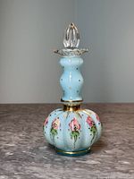 Front view of Fenton blue glass perfume bottle with melon shape and floral decoration.