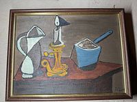Front view of signed mid century cubist style oil on board painting showing pitcher, candle holder, and blue container on table.