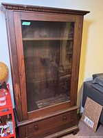 Front view of the bookshelf showing large glass door and bottom drawer