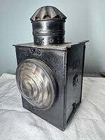 Front and side view showing black metal body and clear ribbed round glass lens with ventilated chimney top