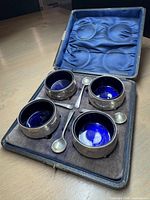 Open case showing four cellars and four spoons fitted in velvet base