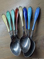 Eight spoons loose on wood surface showing enamel colors and spoon bowls
