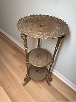 Full view of the three tier cast iron stand showing detailed embossed patterns and claw feet.