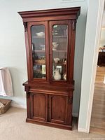 Full view of Victorian bookcase showing upper glass doors with shelving and lower wood paneled doors.
