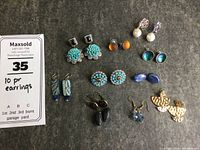 Photo showing 10 pairs of pierced earrings including turquoise, stone, pearl, orange, blue, and metal fan designs.
