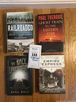 All four railroad books shown from top view, covers visible. Titles: Railroaded, Ghost Train to the Eastern Star, The Race Underground, Empire Express. Price tag included in the shot.