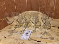Photo showing all 8 clear glass wine glasses grouped together on a wooden surface.
