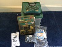 Full lot showing green Brother P-touch PT-65 label maker on top of carrying case, boxed label tape, and additional sealed label tape cartridges.