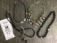 Full view of the lot showing four necklaces, one silver-tone bangle, and one pair of earrings arranged on a grey felt surface.