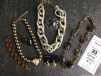 Wide view of all costume jewelry items arranged on dark fabric surface: 3 necklaces, 2 pairs of earrings, 1 brooch, and 1 bracelet.