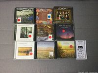 Nine CDs arranged in three rows, featuring folk and winter solstice themed albums, some with red circle stickers.