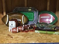 Photo showing three football-shaped trays, rectangular football field tray, small football dish, football-themed napkins, and large football-shaped mug.