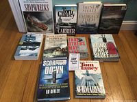 Photo showing all 10 maritime books arranged in two rows within a plastic storage box, covers visible and titles readable.