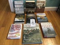 Nine history books on a wooden floor arranged in three rows. Titles visible include various historical and military subjects.